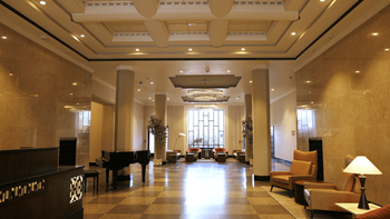 A grand room with a piano, chairs, and a large window.